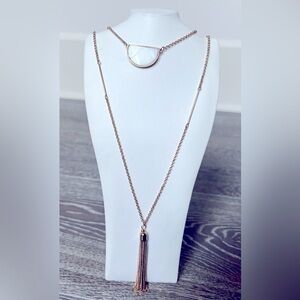 Gold tone long necklace with white pendant and gold tassel